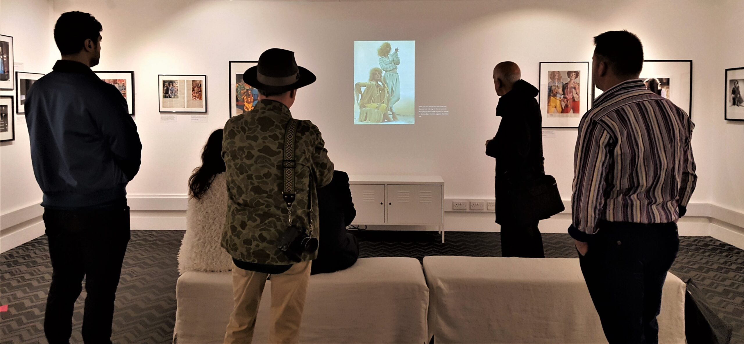 Guests of Terence Pepper and Grace Lee at a curator talk relating to the Beautiful People Photographs. Here they discuss a slide showing Ossie Clark and Alice Pollock two-pieces from Quorom worn with wigs by Troy at Leonards, photograph by Hans Feurer as part of an editorial by Caroline Baker for Nova magazine, September 1969. Fashion and Textile Museum gallery photo: Emma Boden 